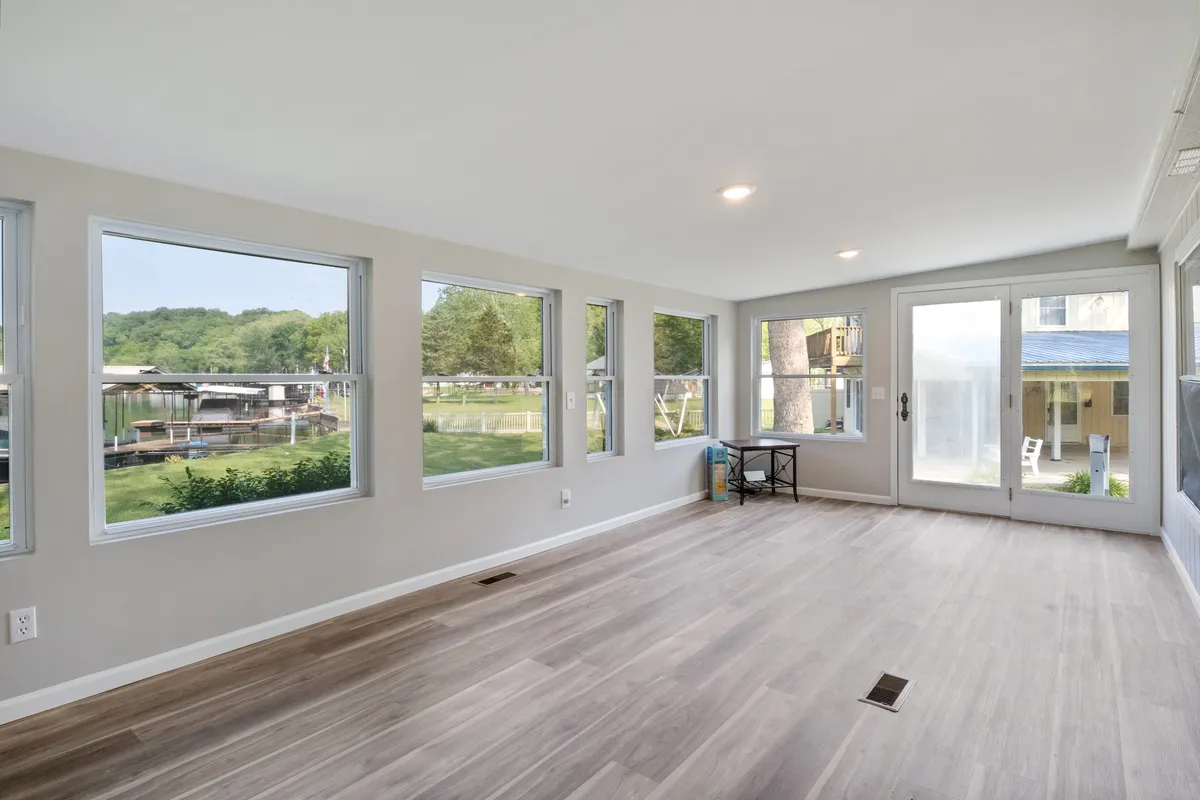 A spacious room with expansive windows offering a clear view of the lake, ample natural light, and an airy open space perfect for both relaxation and socializing. The connection to the outdoors enhances the sense of security and serenity.
