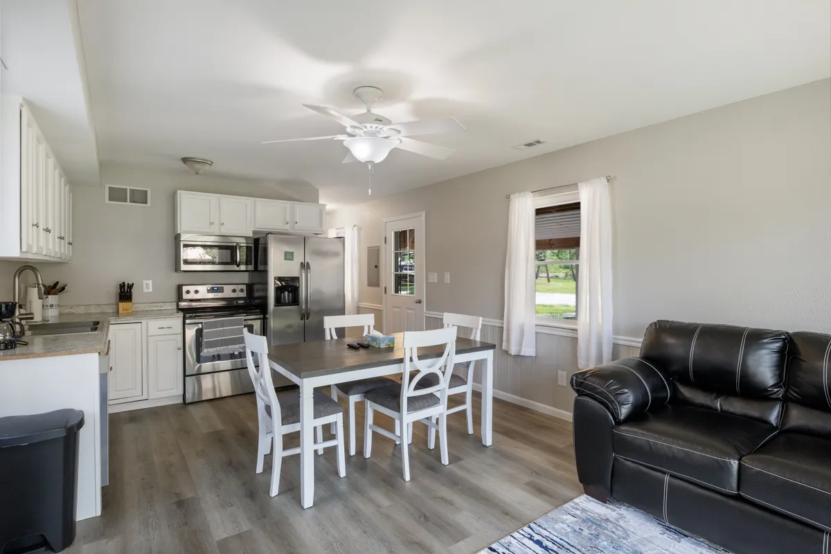 A spacious, inviting kitchen and dining area with modern appliances, a large dining table, and a comfortable sofa nearby. The setting exudes warmth and encourages gathering for meals or casual conversations.