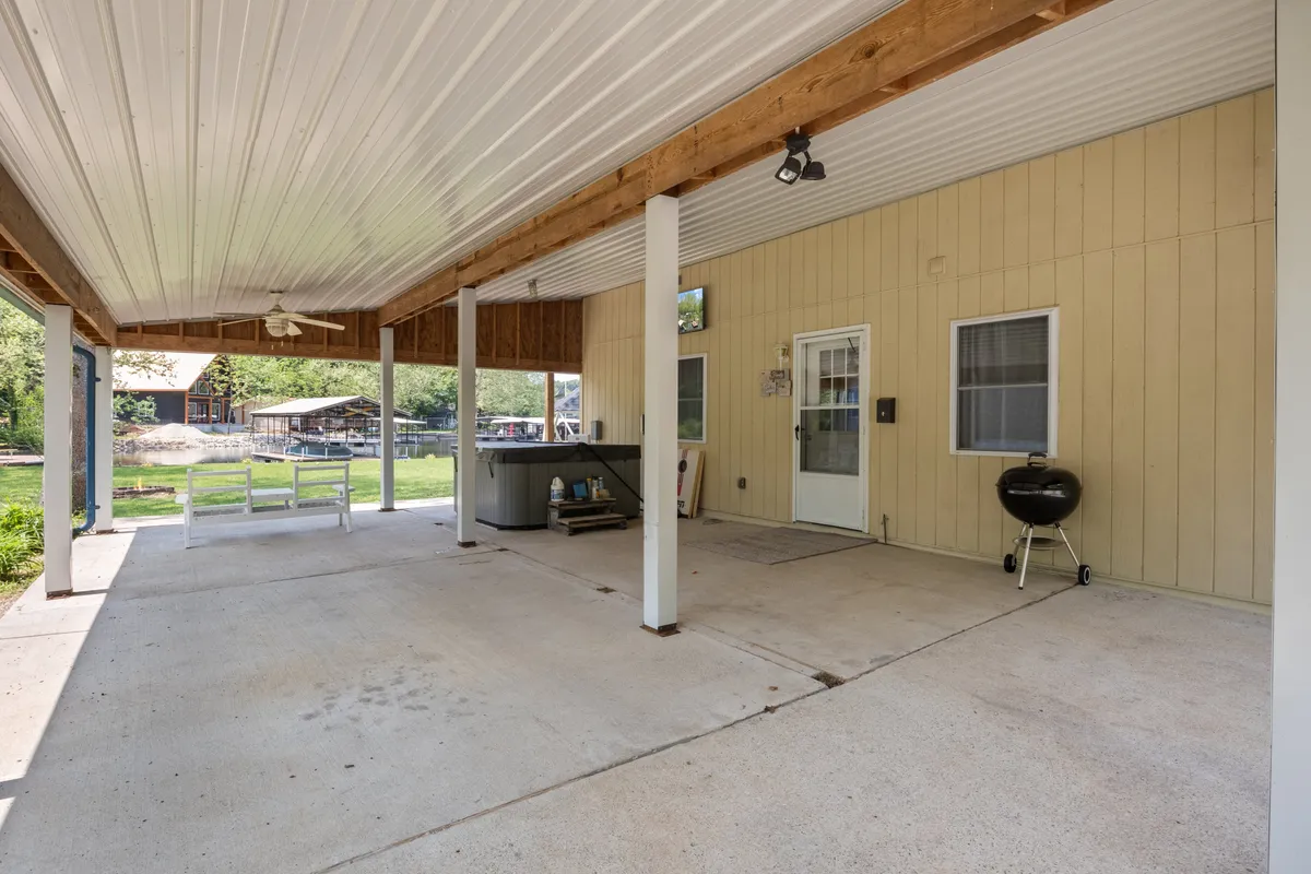 The image showcases a covered outdoor patio with a hot tub and grill, designed for relaxing, entertaining, or dining under the stars. The setting suggests casual outdoor gatherings and leisure time, with the potential for host-curated experiences like starlit nights or lively summer parties.
