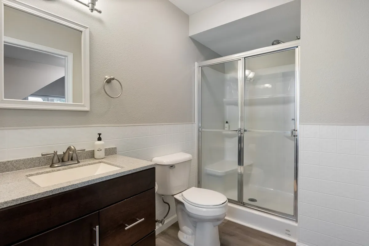 A well-appointed bathroom with a sink and vanity, modern shower enclosure, and a large mirror. The scene is clean and organized, with natural light highlighting the fresh, inviting atmosphere. The amenities are clearly in place, suggesting that necessities are stocked for guest convenience.