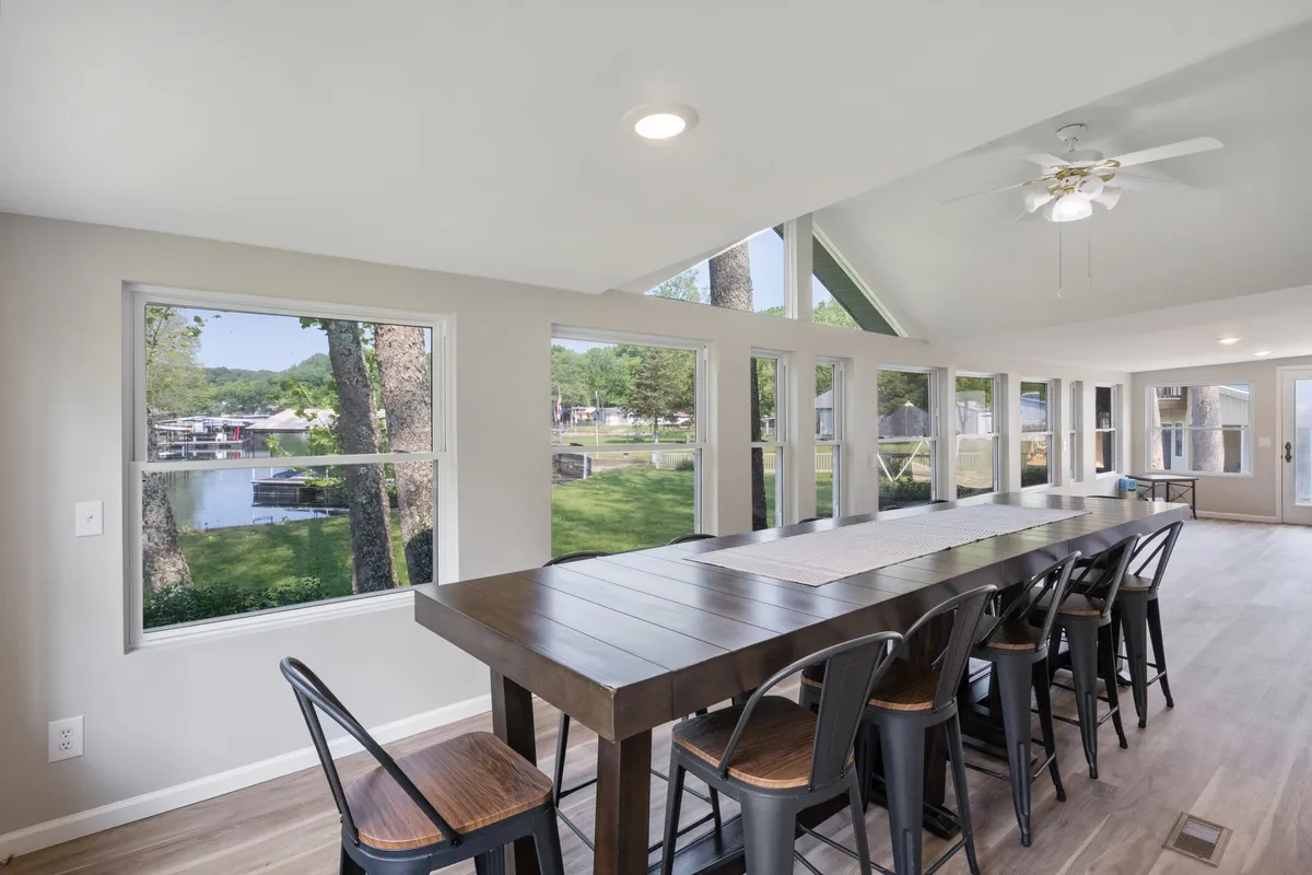 A bright, welcoming dining area with a long table, large windows overlooking the lake, and plenty of seating for group meals. The room is filled with natural light, creating a cheerful atmosphere ideal for gatherings.